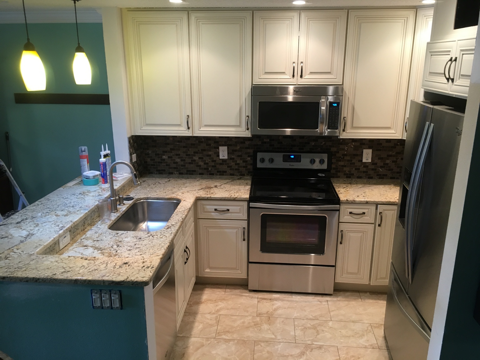 Kitchen with cream cabinets, a stone countertop, and stainless appliances